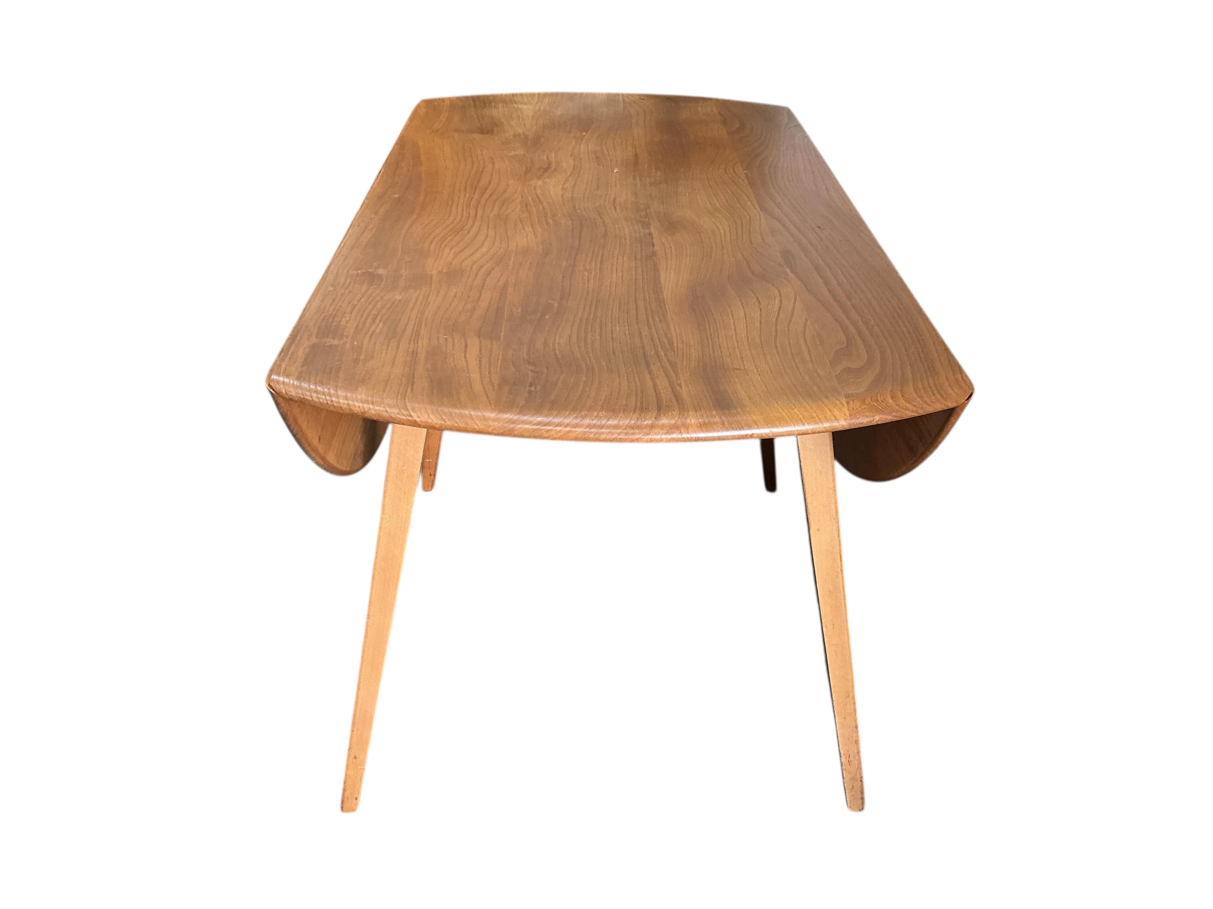 An Ercol elm and beech drop leaf dining table, width 112cm, depth 62cm, height 72cm and four Ercol elm and beech comb back dining chairs